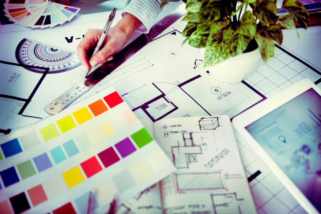 A designers work station, with their tools, plans and colour swatches. 